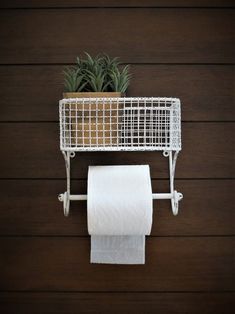 a white toilet paper holder with a plant in it and a roll of toilet paper