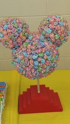 a mickey mouse head made out of buttons on top of a red stand in front of a yellow wall