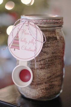 a glass jar filled with brown stuff on top of a table next to a christmas tree