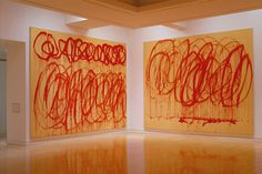 two large paintings on the wall in an art gallery, one is orange and the other is red