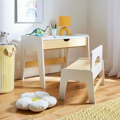 a child's desk and chair in a white room with yellow accessories on the floor