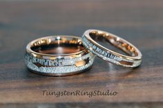 two wedding rings sitting on top of a wooden table