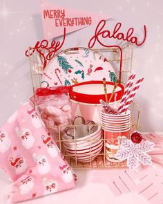 a basket filled with lots of christmas items on top of a pink table cloth and napkins