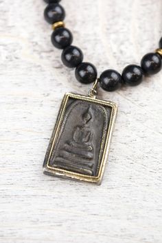 A DharmaShop exclusive 108 bead mala made from powerful, unique materials with a story! Features 108 shungite beads and a handcrafted vintage Buddha protection amulet from Thailand. Shungite is known as one of the most powerful mineral healers. It has the ability to protect and purify. Black stones like shungite are known to offer protection to the wearer, provide stability, and ground the Root Chakra. Over a decade ago, during a trade with a Tibetan artifacts collector, we received a small bag Black Amulet Jewelry For Meditation, Black Gemstone Beads Mala For Healing, Handmade Black Mala For Meditation, Spiritual Obsidian Necklaces For Meditation, Handmade Black Mala As Gift, Black Spiritual Mala For Healing, Black Rectangular Spiritual Jewelry, Black 108 Beads Mala For Meditation, Spiritual Black Beads Mala For Meditation