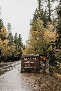 the sign for glacier national park is in front of trees with yellow and orange leaves