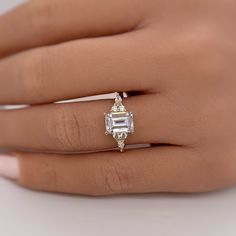 a woman's hand with a diamond ring on her left hand and an emerald stone in the middle