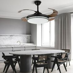 a dining room table with four chairs and a ceiling fan in the middle of it