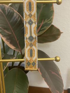 the beaded bracelet is hanging on a metal rack next to a potted plant