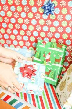 a woman is wrapping christmas presents on the floor with colorful wrapping paper and twine bows