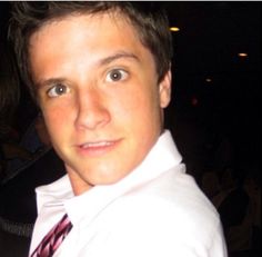 a young man wearing a white shirt and tie posing for a photo with his hands in the air