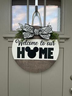 a welcome to our home sign hanging on the front door with a bow and wreath