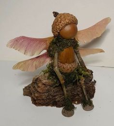 a figurine of a fairy sitting on top of a tree stump with wings