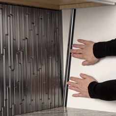 two hands reaching up to the side of a wall with metal slats on it