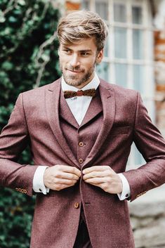 a man in a suit and bow tie is posing for the camera with his hands on his hips