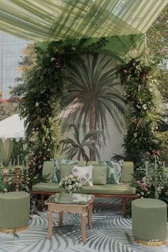 a living room with couches, tables and chairs under a canopy covered in greenery