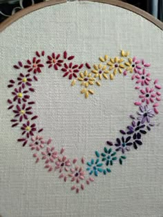 a cross stitch pattern with colorful flowers in the shape of a heart on a white background