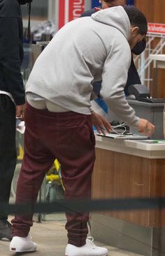 a man standing in front of a counter while wearing a mask and looking at his cell phone