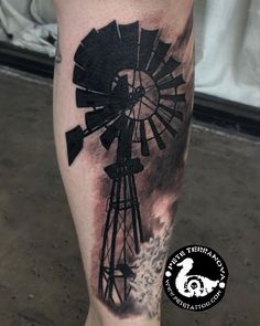 a man's leg with a black and white tattoo of a windmill on it