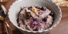 a bowl filled with oatmeal and blueberries on top of a wooden table