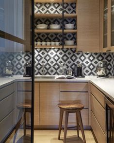 a kitchen with wooden cabinets and white counter tops next to a bar stool in front of a sink