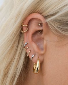 a woman with blonde hair wearing three different ear piercings