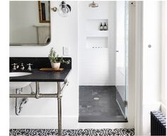 a bathroom with a sink, mirror and shower stall in the corner next to a tiled floor