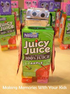 a robot made out of juice bottles sitting on top of a wooden table next to other boxes