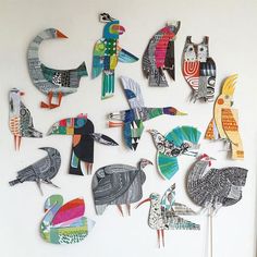 many birds are made out of paper on a white wall and placed in the shape of letters