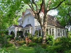 a large white house surrounded by trees and bushes