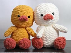 two crocheted stuffed animals sitting next to each other on top of a table