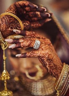 a woman with henna on her hands and jewelry around her neck, holding onto the arm of another woman's hand