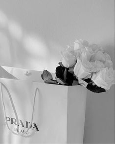 a bouquet of flowers sitting on top of a white bag with the word prada in it