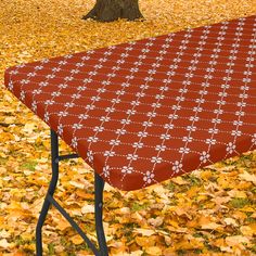 an ironing board on top of a table covered in leaves next to a tree