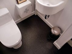 a white toilet sitting next to a sink in a bathroom on top of a black floor