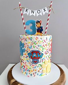 a birthday cake decorated with sprinkles, candles and an animal on top