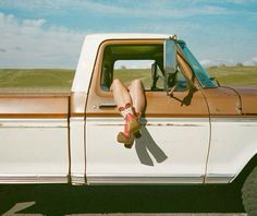 a person sitting in the bed of a truck with their feet up on the hood