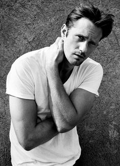 black and white photograph of a man with his hand on his neck, leaning against the wall