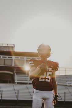 a football player in uniform standing on the field with his arm around his chest and holding a ball