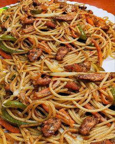 some noodles with meat and vegetables on a white plate