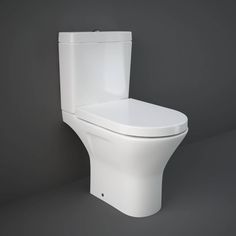 a white toilet sitting in a bathroom next to a gray wall with the lid up