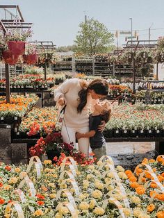 two women and a child standing in front of flowers at a flower shop with lots of orange and yellow flowers