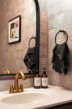 a bathroom sink with gold faucet and two hand towels hanging on the wall