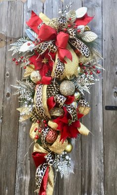 a christmas wreath hanging on the side of a wooden fence with ornaments and ribbons around it