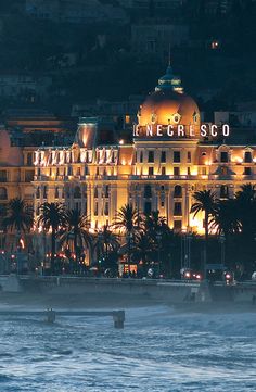 a large building lit up at night by the ocean