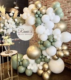 the balloon arch is decorated with gold, white and green balloons for an elegant look