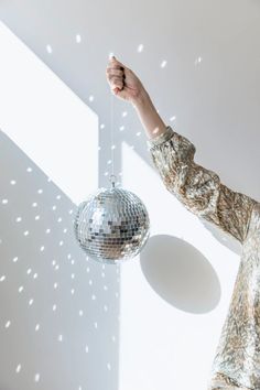 a woman holding a disco ball in her right hand and pointing to the light coming through it