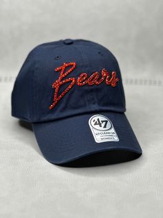 This is a navy CHI Bears script 47 clean up adjustable hat that is hand embellished with varying sizes of genuine transparent orange Swarovski crystals on the front text. This hat features over 150+ varying size Swarovski crystals. - 100% Cotton - Matching fabric strap & buckle - One Size Fits All - Raised Embroidered Logo - 150+ Swarovski orange crystals individually placed by hand - Ready to ship in 1 week from San Diego, CA Navy Curved Brim Hat For Game Day, Casual Cap With Rhinestones, Casual Rhinestone Cap, Navy Adjustable Baseball Cap For Fans, Adjustable Curved Brim Baseball Cap For Game Day, Adjustable Rhinestone Baseball Cap With Curved Brim, Adjustable Curved Brim Hats For Fan Gear, Adjustable Curved Brim Fan Gear Hats, Casual Rhinestone Snapback Hat