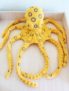 an octopus made out of crochet sits in a box