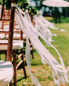 the chairs are lined up with ribbons and flowers on them for an outdoor wedding ceremony