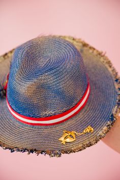 Sail into the summer with our BON VOYAGE SUN HAT! This stylish blue and gold hat features a bold red and white striped ribbon band and a playful gold sailboat pin. Finished with a patriotic red, white, and blue feather combo, it's perfect for any beach day or boat trip. This hat is ONE OF A KIND, created by our owner Stephanie. To receive item quicker, expedited shipping is available at checkout. Red Patriotic Beach Hat, Patriotic Red Beach Hat, Patriotic Red Hat For Beach, Nautical Beach Hat With Curved Brim, Nautical Style Beach Hat With Curved Brim, Red Beach Hat For 4th Of July, Nautical Navy Beach Hat, Patriotic Blue Beach Hat, Navy Nautical Beach Hat